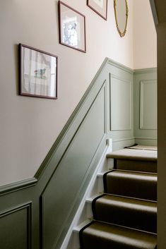 some stairs with pictures on the wall and carpeted steps leading up to them in a home