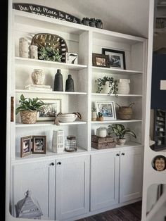 a white bookcase filled with lots of books and vases on top of it