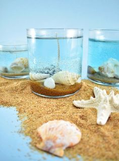 three glass vases filled with sand and shells