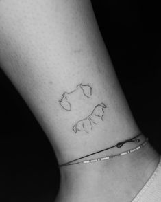 a small tattoo on the ankle of a woman's foot, depicting two horses