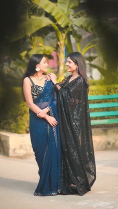 two women standing next to each other on a bench