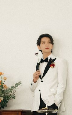 a man in a tuxedo holding a flower