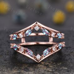 a rose gold ring with blue topazte and diamonds on the side, sitting on a stone surface