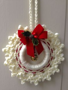 a crocheted christmas ornament hanging on a door with a red bow