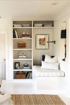 a living room filled with lots of white furniture and bookshelves on top of each other