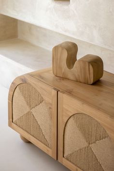 a close up of a wooden object on top of a table in a room with white walls