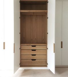 an open closet with drawers and cupboards in the corner, next to a white wall