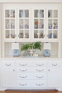 a white china cabinet with blue and white dishes on it