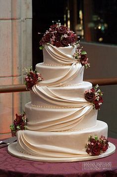 a three tiered white wedding cake with red flowers