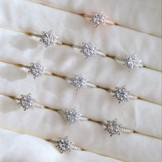 six wedding rings are arranged in rows on a white cloth with pearls and diaper