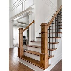 a staircase with wooden handrails and white walls in a home's entryway