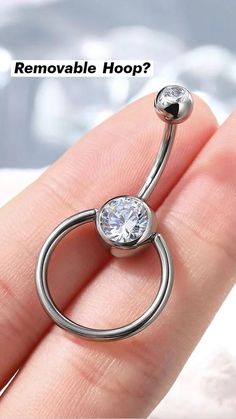 a person's hand holding an open belly ring