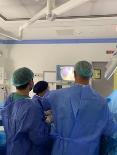 three doctors in scrubs watching tv in the operating room