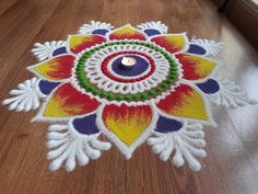 a colorful flower design on the floor with a candle in it's center,