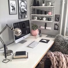 a white desk topped with a computer monitor next to a book shelf filled with books