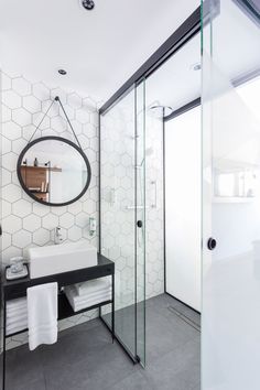 a bathroom with a sink, mirror and shower stall in the corner on the wall