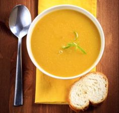 a bowl of soup next to a piece of bread