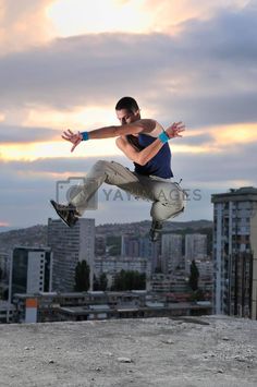 a man is jumping in the air with his arms out and buildings in the background