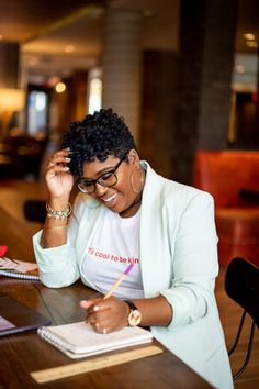 a woman sitting at a table with a notebook and pen