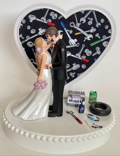 a wedding cake topper with a bride and groom in front of a heart shaped clock