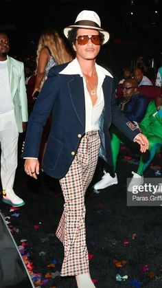 a man in plaid pants and a white hat walking through confetti covered ground