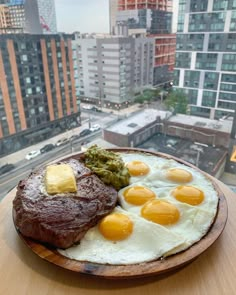 two eggs and some meat on a plate in front of a cityscape with high rise buildings