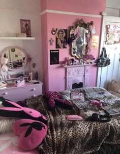 a bedroom decorated in pink and black with leopard print bedding, dressers, mirror and other accessories