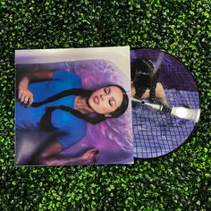 a woman laying on top of a lush green field next to a tennis racquet