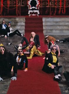 a group of people sitting on top of a red carpet