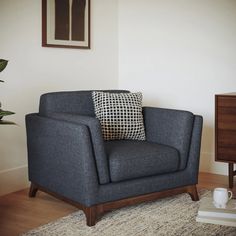 a blue chair with a black and white pillow on top of it next to a table