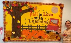 a woman standing in front of a bulletin board with fall leaves and pumpkins on it