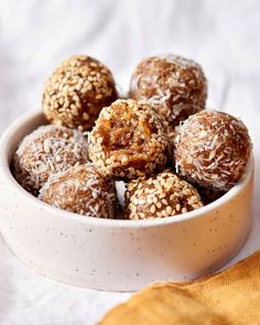 a bowl filled with chocolate covered donuts sitting on top of a white table cloth