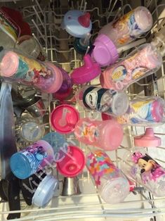 a dishwasher filled with lots of baby bottles and cups next to utensils