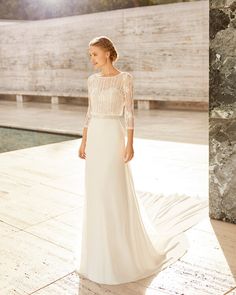 a woman in a white wedding dress standing on a stone walkway next to a pool