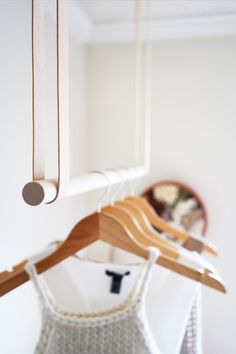 some clothes hanging on wooden hangers in front of a white wall and a mirror