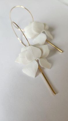 three white flowers are sitting on top of each other, with gold stems in the middle