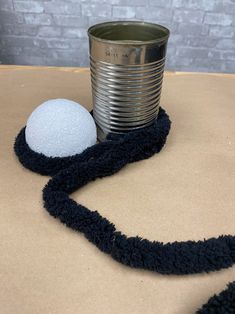 a tin can sitting on top of a table next to a black and white ball