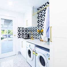 a washer and dryer in a white laundry room with black and white tiles