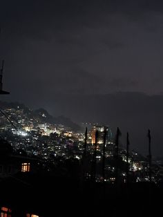 the city is lit up at night with lights in the buildings and dark clouds overhead