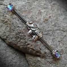 an antique looking metal bar with purple crystal stones on it's end, sitting on top of a rock