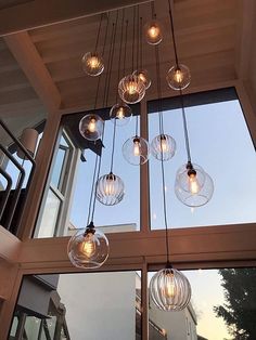 a bunch of lights that are hanging from the ceiling in front of a window and some windows