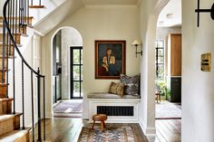 an entryway with a bench and stairs leading to the second floor, along with a painting on the wall