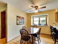 a dining room table with four chairs and a ceiling fan