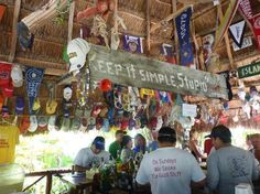 several people are sitting at a bar with flags hanging from the ceiling and signs above them