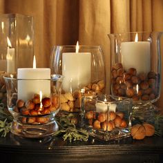 candles are lit in glass vases with nuts and greenery