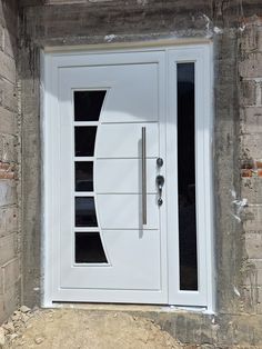 a white door on a brick wall in front of a doorway with glass inserts