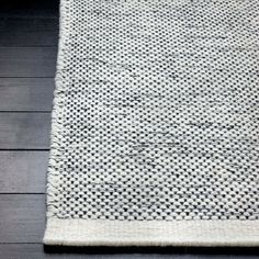 a white and black rug on top of a wooden floor