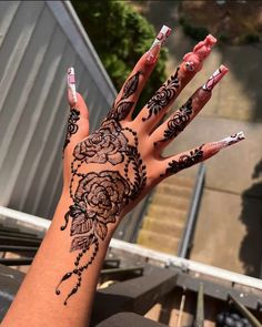 a woman's hand with henna tattoos on it and nails painted to look like roses