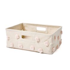 a white storage basket with pink pom - poms on the handles and bottom