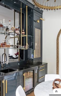 a kitchen with black cabinets and marble counter tops, gold trimmings on the doors